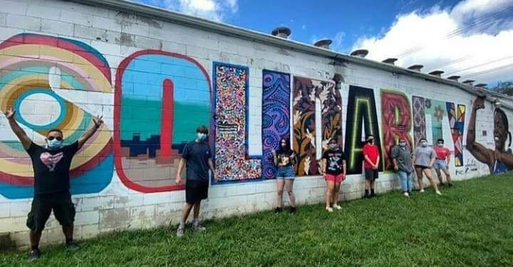 Community members standing with the completed Solidarity mural